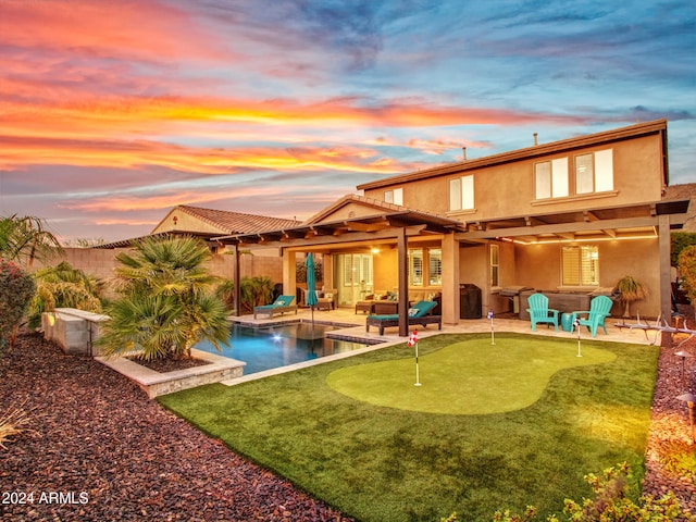 back house at dusk with an outdoor living space and a patio