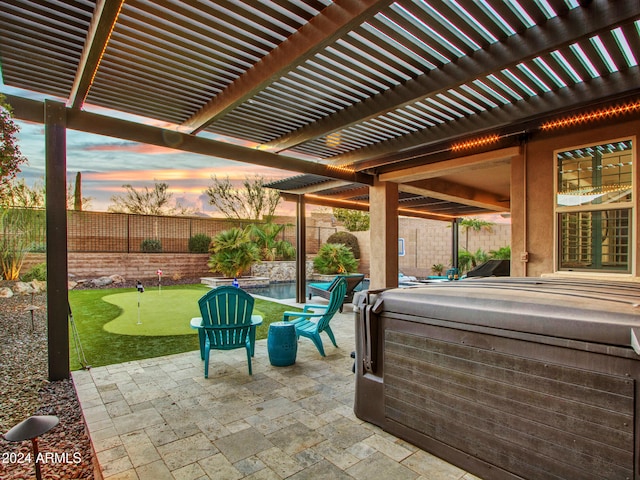 patio terrace at dusk featuring a pergola and a hot tub