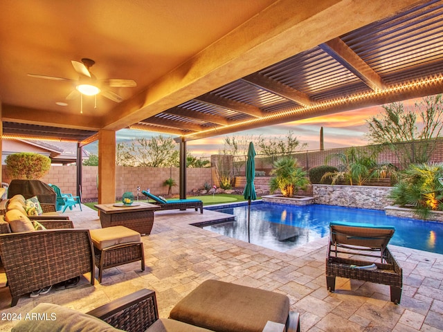 pool at dusk featuring a patio area, ceiling fan, and pool water feature