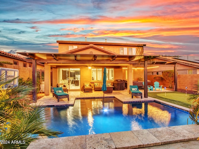 pool at dusk with an outdoor hangout area, a patio, and ceiling fan