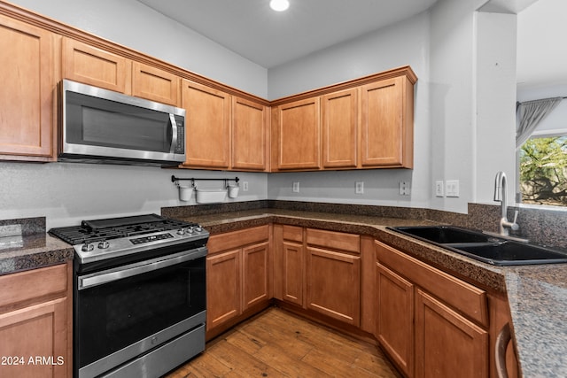 kitchen featuring stainless steel appliances, light hardwood / wood-style flooring, and sink