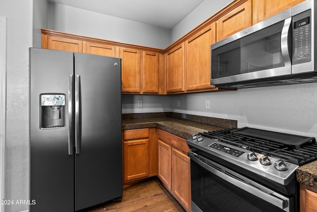 kitchen featuring dark stone countertops, stainless steel appliances, and hardwood / wood-style flooring