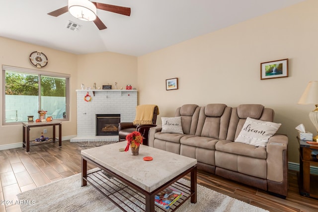 living room featuring ceiling fan, a fireplace, and vaulted ceiling