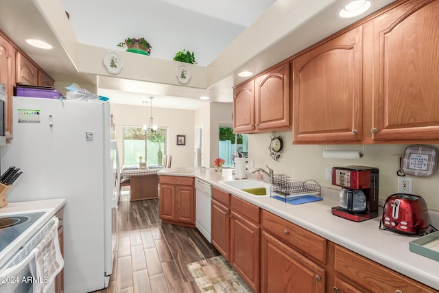 kitchen with white appliances, an inviting chandelier, hanging light fixtures, and sink