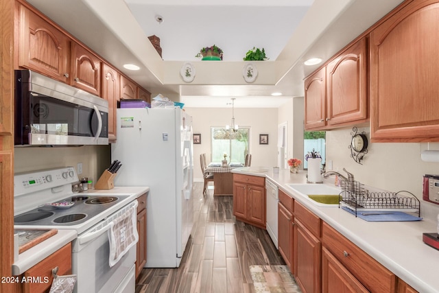 kitchen featuring sink, dark wood-type flooring, an inviting chandelier, decorative light fixtures, and white appliances