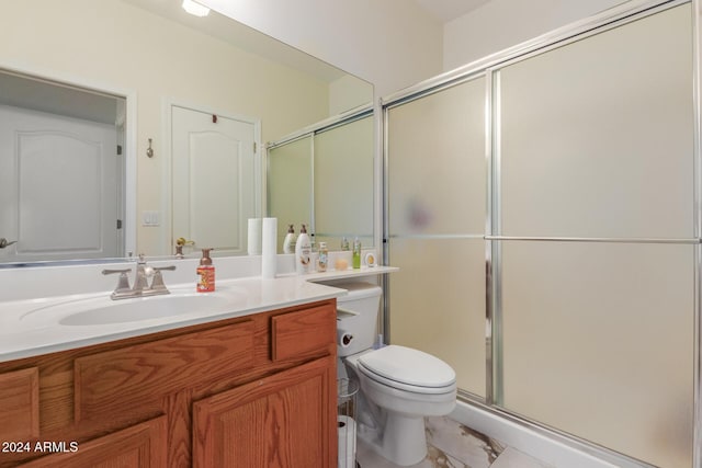 bathroom featuring vanity, toilet, and an enclosed shower