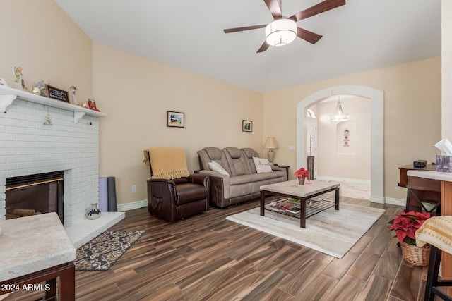 living room with ceiling fan, a fireplace, and dark wood-type flooring