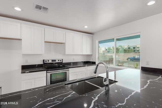 kitchen featuring white cabinets, stainless steel electric range, dark stone countertops, and sink