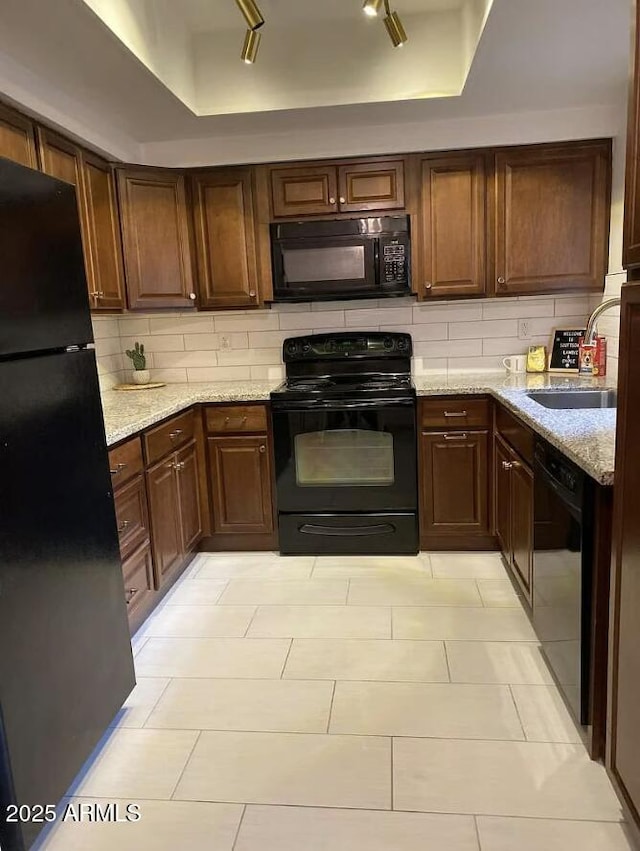 9451 E Becker Ln Unit 1051, Scottsdale, AZ 85260 - kitchen with black appliances, backsplash, a sink, light stone countertops, and a tray ceiling