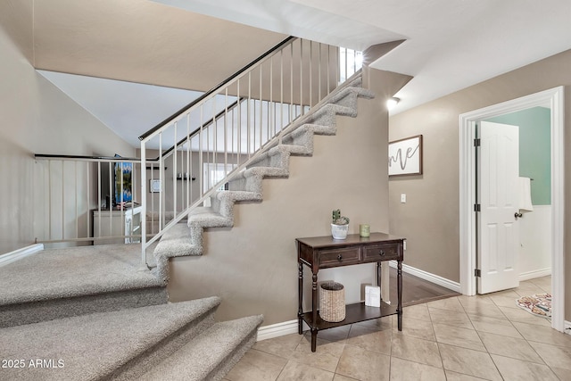 stairway with tile patterned floors and lofted ceiling