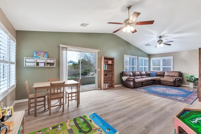 living room with ceiling fan, vaulted ceiling, and light wood-type flooring