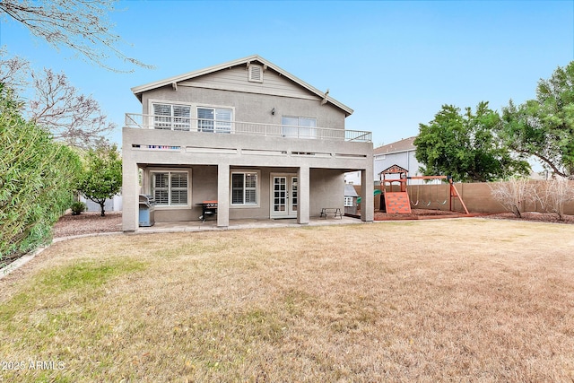 back of house featuring a balcony, a yard, a playground, and a patio area