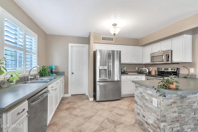 kitchen featuring white cabinets, kitchen peninsula, sink, and appliances with stainless steel finishes