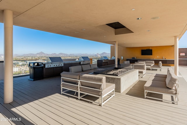 wooden deck featuring exterior kitchen, area for grilling, an outdoor living space, and a mountain view