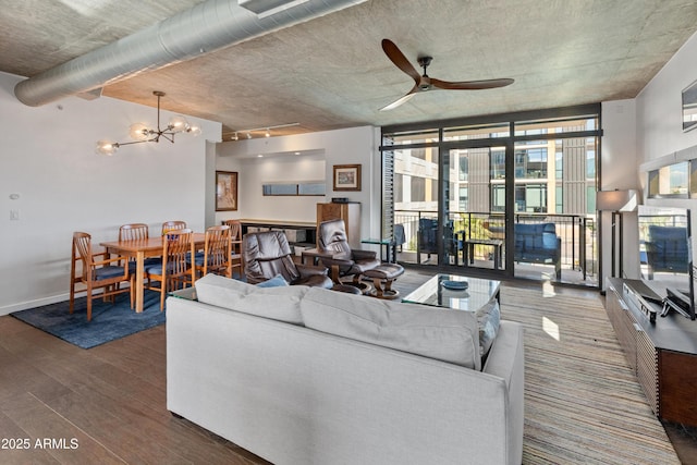 living room with dark wood-type flooring, a wall of windows, track lighting, and ceiling fan with notable chandelier