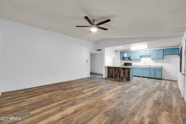 kitchen with blue cabinets, sink, range, vaulted ceiling, and dark hardwood / wood-style floors