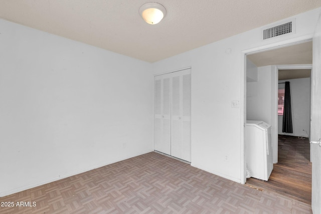 empty room featuring washer / clothes dryer, a textured ceiling, and light parquet flooring