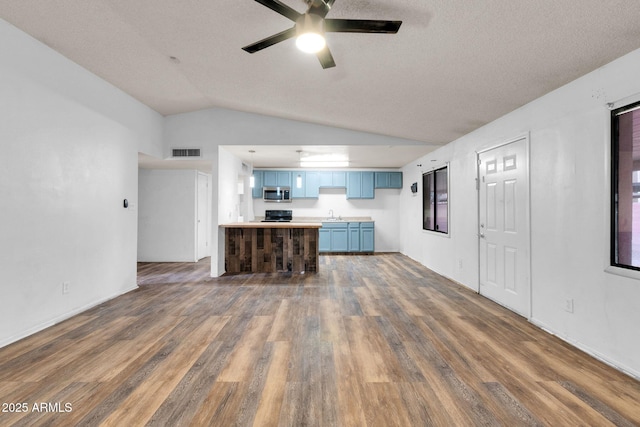 kitchen featuring dark wood-type flooring, sink, vaulted ceiling, kitchen peninsula, and ceiling fan