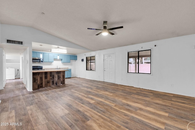 unfurnished living room with lofted ceiling, sink, wood-type flooring, ceiling fan, and washing machine and dryer