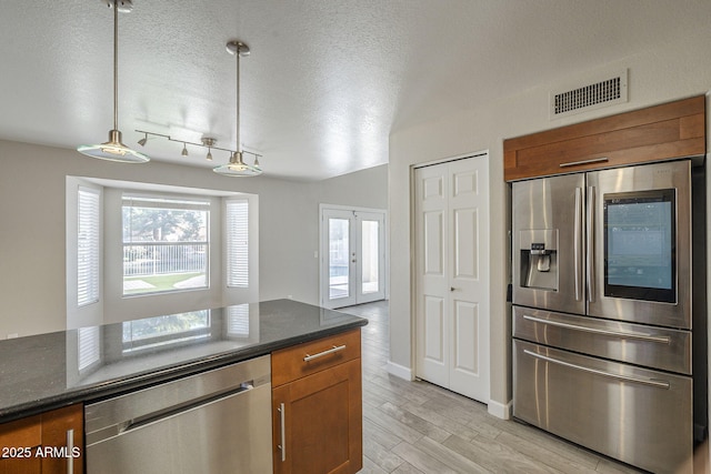 1610 W Maplewood St, Chandler, AZ 85286 - kitchen with stainless steel appliances, brown cabinets, healthy amount of natural light, light wood-style floors, and a textured ceiling