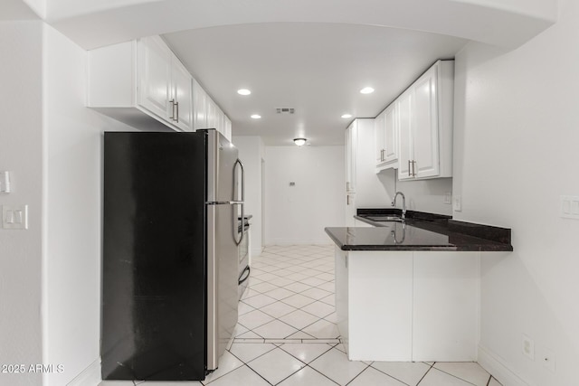 kitchen featuring sink, white cabinetry, light tile patterned floors, stainless steel refrigerator, and kitchen peninsula