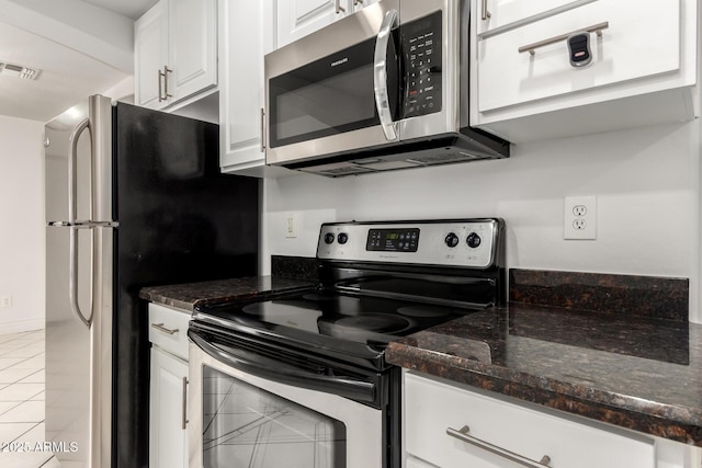 kitchen with white cabinetry, light tile patterned flooring, dark stone counters, and appliances with stainless steel finishes