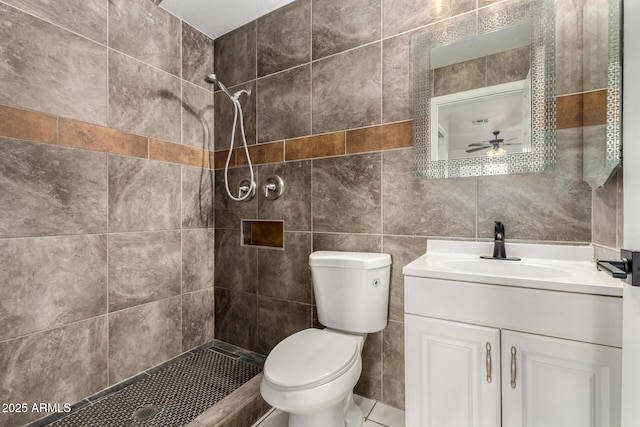 bathroom with vanity, tile walls, toilet, and tiled shower