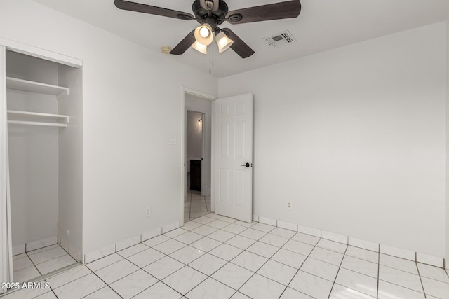 unfurnished bedroom with light tile patterned flooring, ceiling fan, and a closet