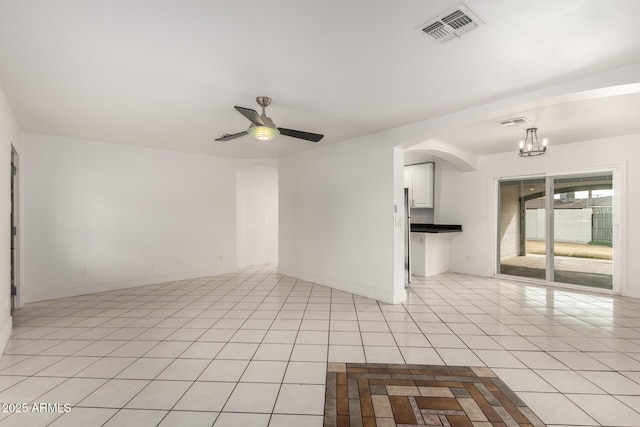 spare room featuring light tile patterned floors and ceiling fan with notable chandelier