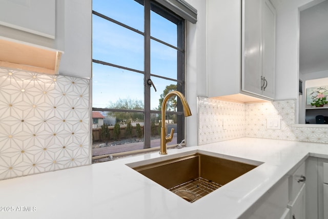 kitchen featuring white cabinetry, sink, and backsplash