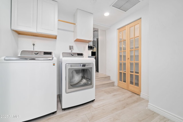 laundry area with cabinets, washer and clothes dryer, and light hardwood / wood-style flooring