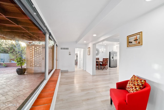 corridor with an inviting chandelier, hardwood / wood-style flooring, and a wealth of natural light