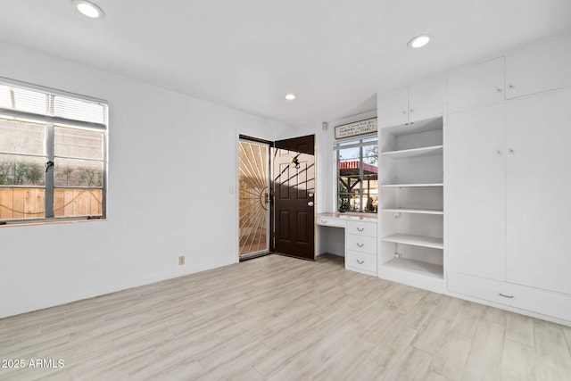 unfurnished bedroom featuring built in desk and light hardwood / wood-style flooring