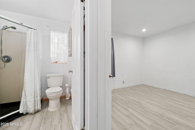 bathroom with hardwood / wood-style flooring, curtained shower, and toilet