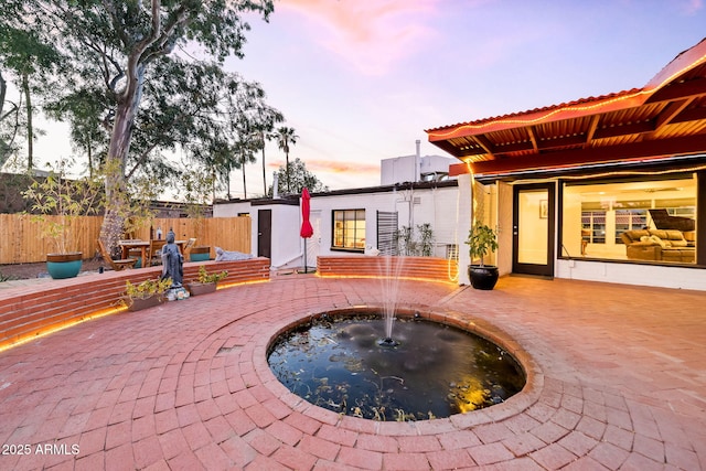 patio terrace at dusk featuring pool water feature