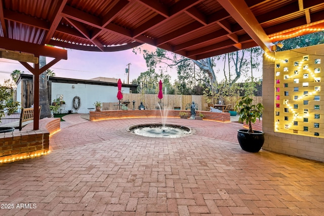 patio terrace at dusk featuring pool water feature