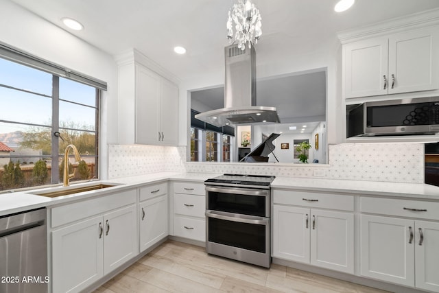 kitchen with stainless steel appliances, island exhaust hood, sink, and white cabinets