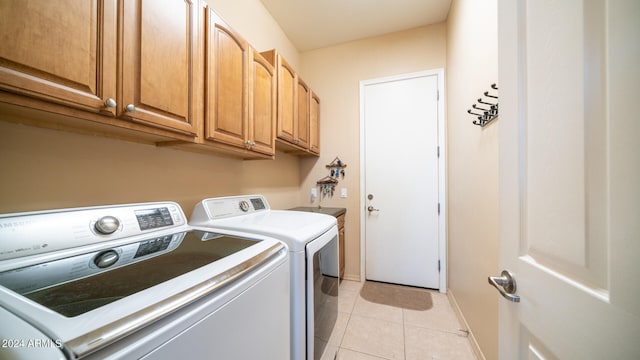 laundry area with cabinets, washing machine and dryer, and light tile patterned floors