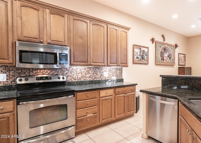 kitchen featuring tasteful backsplash, stainless steel appliances, light tile patterned floors, and dark stone countertops