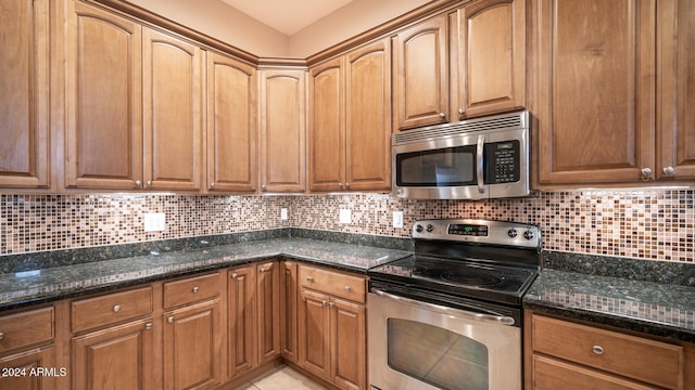 kitchen with appliances with stainless steel finishes, dark stone counters, and backsplash