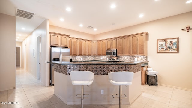 kitchen with a breakfast bar, appliances with stainless steel finishes, decorative backsplash, and a center island