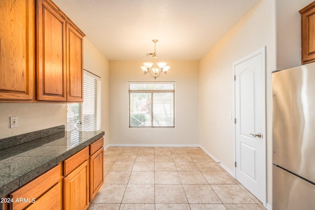 kitchen featuring decorative light fixtures, an inviting chandelier, stainless steel refrigerator, and light tile floors