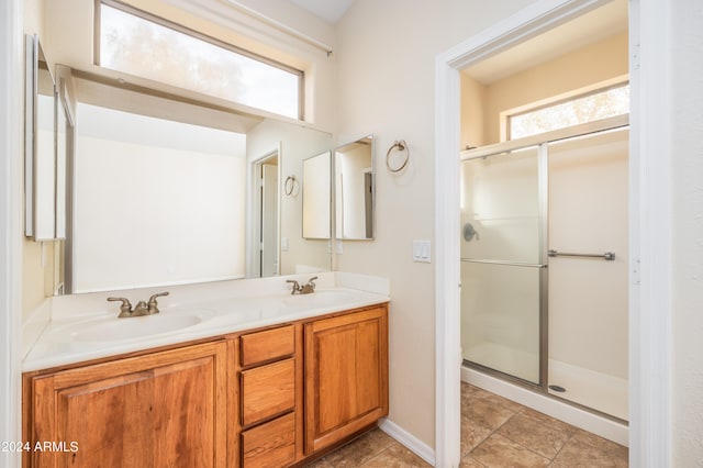 bathroom featuring dual vanity, tile floors, and a shower with door