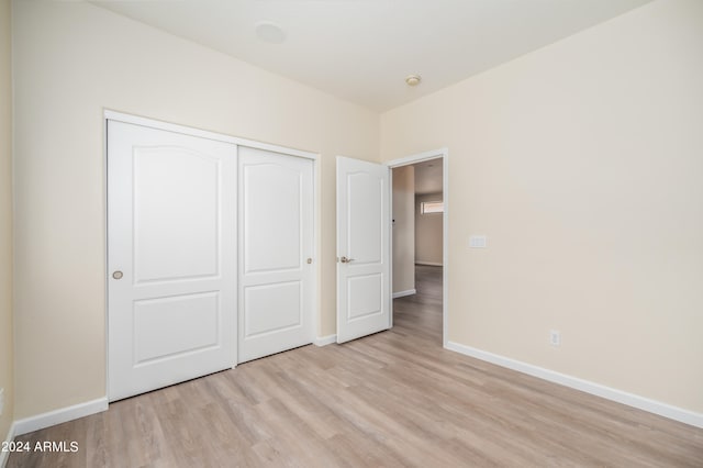 unfurnished bedroom with light hardwood / wood-style flooring and a closet