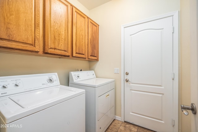 washroom with light tile floors, cabinets, and washer and clothes dryer