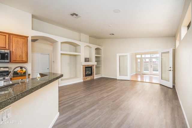 interior space with dark wood-type flooring, lofted ceiling, a fireplace, built in shelves, and french doors