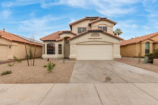 mediterranean / spanish-style home featuring stucco siding, a garage, driveway, and a tiled roof