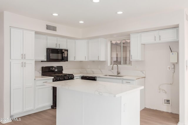 kitchen featuring white cabinetry, black appliances, visible vents, and a sink