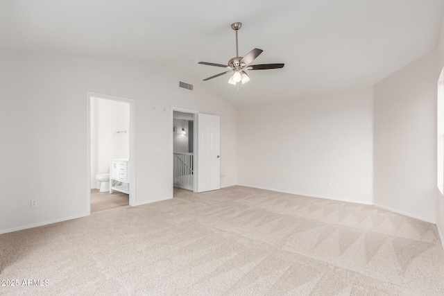 interior space featuring visible vents, baseboards, vaulted ceiling, light carpet, and ensuite bathroom