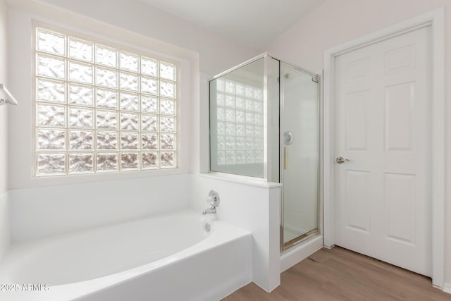 bathroom with a shower stall, a bath, a healthy amount of sunlight, and wood finished floors